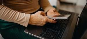 Mani che usano lo smartphone accanto al portatile